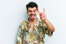 Young Caucasian Man Isolated On Blue Background Showing A Horns Gesture As A Revolution Concept.