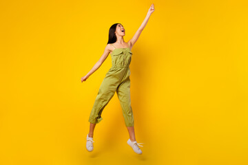 Wall Mural - Full length portrait of crazy energetic vietnamese girl look arm hold empty space umbrella isolated on yellow color background