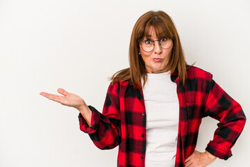 Wall Mural - Middle age caucasian woman isolated on white background showing a copy space on a palm and holding another hand on waist.