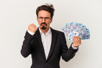 Wall Mural - Young caucasian man holding banknotes isolated on white background showing fist to camera, aggressive facial expression.