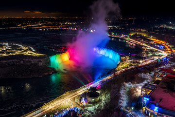 Wall Mural - Aerial view of Horseshoe Falls winter illumination in twilight time. Niagara Falls City downtown horizon. Stunning landscape dusk to night.