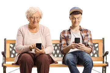 Canvas Print - Elderly woman and a male teenager sitting on a bench and using smartphones