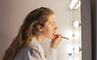 © Denis Kadatsky - woman makes up her lips in front of a mirror