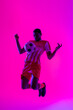 © vectorfusionart - African american male soccer player with football over neon pink lighting