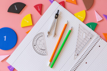 Wall Mural - Back to school background. Open notepad, fractions, chart, pencils on a pastel pink background. Close up parts of yellow math fractions. Back to school, fun study, mathematics