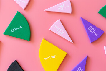 Wall Mural - Violet orange yellow pieces of fractions on a table. Close up math material for study. Back to school, geometry lessons, mathematical education for preschooler. Creative study. background with numbers