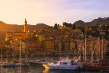 Scenic View Of Boats Moored Against A City With Colorful Old Houses At Sunset