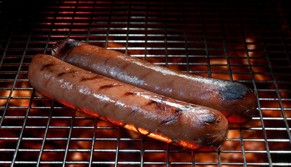 Hot dogs being cooked with stripes over a grill