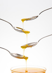 Fresh floral honey drips from a spoon into a spoon on a white background. Organic vitamin food.