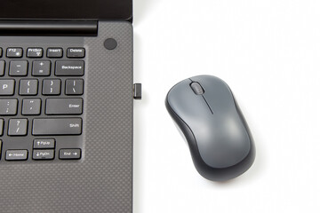 Computer wireless mouse next to a laptop on a white table close-up. electronic personal industry