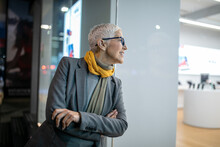 Smiling Mature Senior Woman With Short Gray Hair And Eyeglasses Walking On Street, Night Scene In City