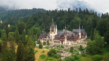 Wall Mural - Aerial drone view of The Peles Castle in Romania. Castle with gardens and tourists in Carpathians, lush forest around it