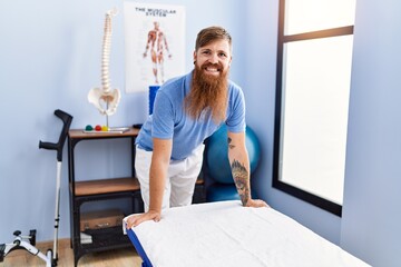 Sticker - Young redhead man wearing physiotherapist uniform standing at physiotherapy clinic