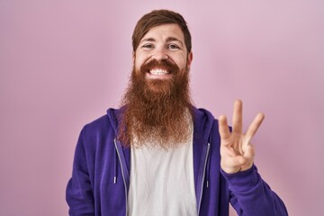 Canvas Print - Caucasian man with long beard standing over pink background showing and pointing up with fingers number three while smiling confident and happy.