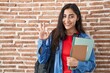 © Krakenimages.com - Young teenager girl wearing student backpack and holding books doing ok sign with fingers, smiling friendly gesturing excellent symbol