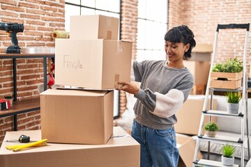 Canvas Print - Young woman smiling confident holding package at new home