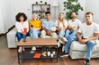 © Krakenimages.com - Group of people eating snack sitting on the sofa at home looking positive and happy standing and smiling with a confident smile showing teeth