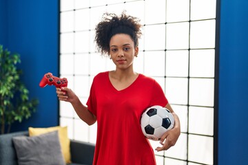 Wall Mural - Young african american woman playing football video game relaxed with serious expression on face. simple and natural looking at the camera.