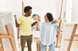 © Krakenimages.com - African american artist couple smiling happy holding paintbrush and palette at art studio.