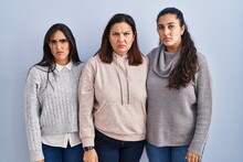 Mother And Two Daughters Standing Over Blue Background Skeptic And Nervous, Frowning Upset Because Of Problem. Negative Person.
