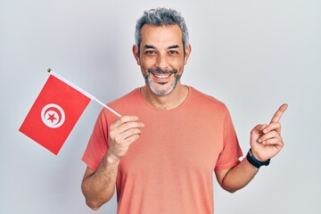 Poster - Handsome middle age man with grey hair holding tunisia flag smiling happy pointing with hand and finger to the side