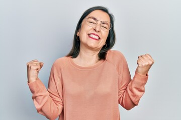 Canvas Print - Middle age hispanic woman wearing casual clothes and glasses very happy and excited doing winner gesture with arms raised, smiling and screaming for success. celebration concept.