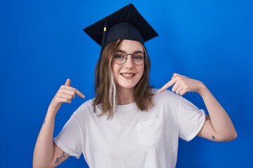 Poster - Blonde caucasian woman wearing graduation cap looking confident with smile on face, pointing oneself with fingers proud and happy.