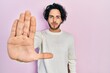 © Krakenimages.com - Handsome hispanic man wearing casual white sweater doing stop sing with palm of the hand. warning expression with negative and serious gesture on the face.