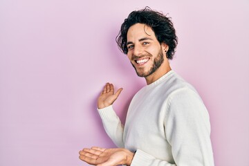 Poster - Handsome hispanic man wearing casual white sweater inviting to enter smiling natural with open hand