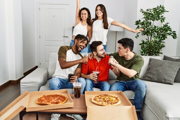 Wall Mural - Group of young friends having party eating italian pizza and singing song at home.