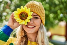 Young Blonde Woman Smiling With Sunflower On Eye At The Park