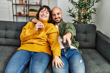 Wall Mural - Young hispanic couple smiling happy watching movie sitting on the sofa at home.