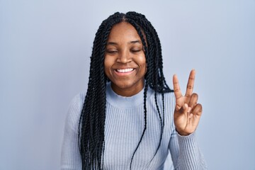 Wall Mural - African american woman standing over blue background showing and pointing up with fingers number two while smiling confident and happy.