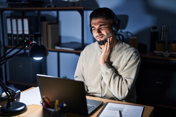 Wall Mural - Young handsome man working using computer laptop at night touching mouth with hand with painful expression because of toothache or dental illness on teeth. dentist