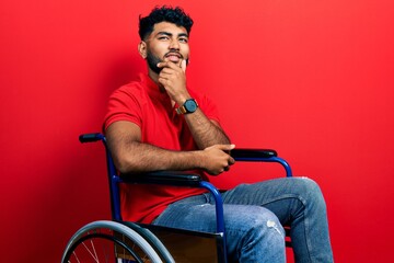 Sticker - Arab man with beard sitting on wheelchair with hand on chin thinking about question, pensive expression. smiling and thoughtful face. doubt concept.