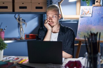 Sticker - Young caucasian man using laptop at night at art studio looking stressed and nervous with hands on mouth biting nails. anxiety problem.