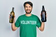 © Krakenimages.com - Young hispanic man wearing volunteer t shirt holding recycling bottle glass smiling with a happy and cool smile on face. showing teeth.