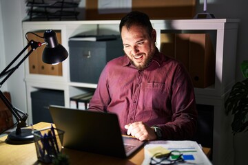 Canvas Print - Plus size hispanic man with beard working at the office at night winking looking at the camera with sexy expression, cheerful and happy face.