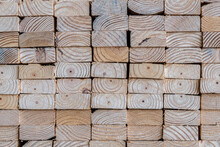 Photograph of the end profile of a stack of 2 x 4 studs in a lumber yard featuring the wood grain