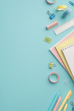 Back To School Concept. Top View Vertical Photo Of Colorful Stationery Notepads Eraser Ruler Adhesive Tape Pens And Binder Clips On Isolated Pastel Blue Background
