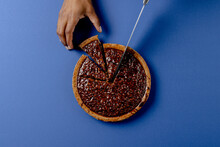 Composition Of Hands Of Biracial Man Cutting Pie With Knife On Blue Background
