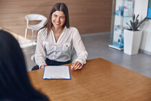 Smiling Caucasian Dark Haired Caucasian Lady Is Filling A Document On Clinic's Reception