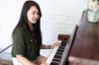 Portrait Happy Smiling beautiful Asian woman wearing brownish green dress stylish hipster with playing old wooden piano Vintage classic style.