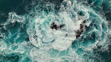 Aerial Top Down View Of Sea Or Ocean Surf Breaking On Rocks. Powerful Wave With White Foam And Turquoise Water. Slow Motion, 4K