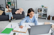 © LIGHTFIELD STUDIOS - girl doing homework near computer and nanny sitting with book on blurred background.