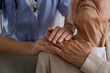 © Evrymmnt - Unrecognizable female doctor expressing care towards an elderly lady, comforting her and holding hands. Two adult women of different age. Family values concept. lose up, copy space, background.