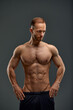 © Georgii - Young male athlete posing. Handsome athletic male power guy. Fitness muscular person. Young athlete showing muscles in the studio, posing shirtless on gray background.