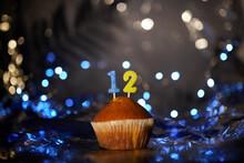 Tasty Vanilla Cupcake Or Muffin With Number 12 Twelve On Aluminium Foil And Blurred Bright Background. Holiday Or Birthday Digital Greeting Card Concept. High Quality Photo