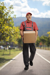 Sticker - Mature delivery man walking outdoors and carrying a box