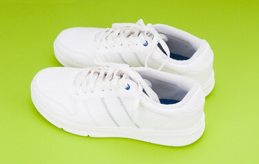 Pair white sport sneakers close up on green background